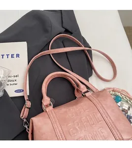 Detail of pink leather handbag with embossed lettering and decorative bead charms