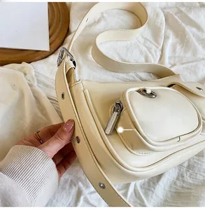 Detail view of cream white shoulder bag featuring a silver metal zipper and D-ring