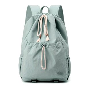 Detail view of mint green nylon backpack with drawstring pockets and cream cotton cords