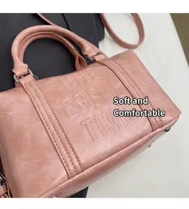 Detailed view of pink Boston bag with embossed lettering and premium leather texture