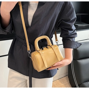 Detail showing ginger yellow mini Boston bag with silver hardware on a model waist