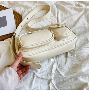 Detail view of the side and bottom of a beige PU leather crossbody bag with side pockets