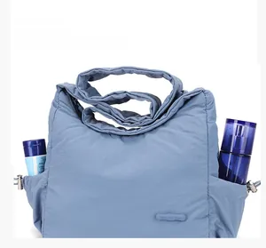 Detail view of side pockets on a light blue pleated nylon shoulder bag for storage