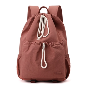 Detail of large capacity brick red nylon drawstring backpack with front pocket and side pockets