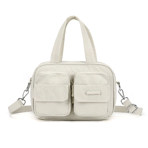 Detail of light beige nylon utility handbag with front zipper pockets and silver hardware