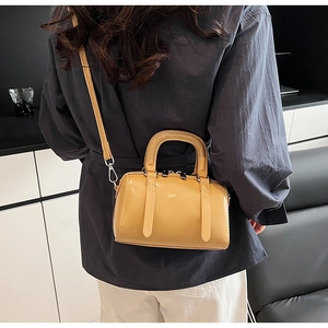 Detail of a bright yellow Boston bag featuring shiny PU leather and silver hardware