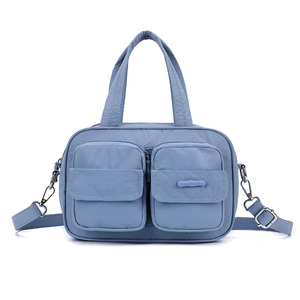 Detailed macro view of dual front zipper pockets on blue nylon functional handbag
