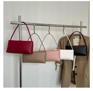 Minimalist leather baguette bags in five colors hanging on a modern display rack