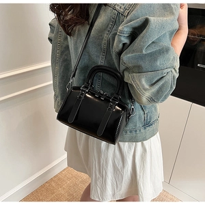 Detail of black glossy Boston handbag with silver hardware shown as a crossbody bag
