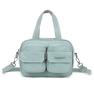 Detail of mint green nylon handbag featuring double handles and front zipper pockets