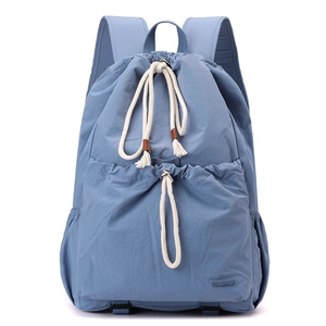 Close-up of light blue nylon drawstring backpack with cotton rope and brand label