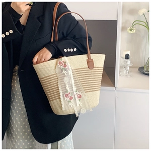 Fashionable straw tote bag with brown stripes and lace ribbon worn by a model