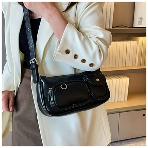 Detail of a black minimalist bag featuring functional zip and snap button pockets