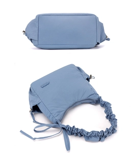 Detail view of the light blue nylon pleated crossbody bag with a branded side logo tag
