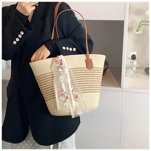 Detail of hand-woven straw tote with striped pattern and floral lace scarf accessory