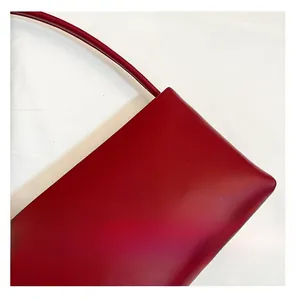 Close-up of a red leather handbag showing slim strap joints and a matte rectangular body