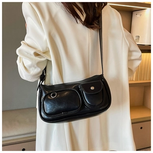 Detail of a black crossbody bag with functional zip and flap pockets on a white blazer