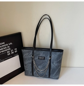 Détail d'un grand sac cabas avec texture marbre gris, décor de chaîne et logo de marque
