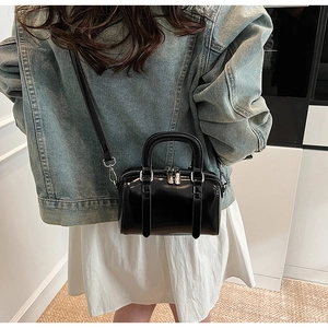 Detail of mini black patent leather Boston bag with silver zippers and dual top handles