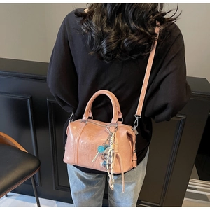 Detailed view of pink Boston bag with embossed lettering and lollipop charm accessory