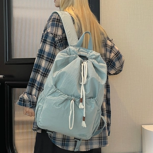 Close-up of light blue nylon drawstring backpack with thick white cords and front pocket