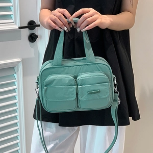 Detail of green utility crossbody bag with double front zip pockets and nylon texture