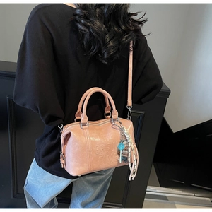 Pink Boston bag with top handles and bear charm shown on a stylish model during commute