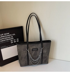 Détail d'un sac cabas gris foncé avec triples chaînes métalliques et texture urbaine