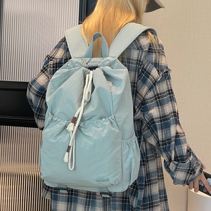 Close-up of light blue nylon drawstring backpack with large front pocket and padded straps