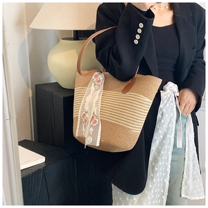 Detail of straw tote bag with brown leather straps and floral lace ribbon decoration