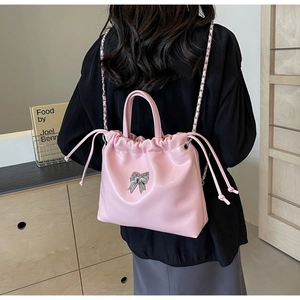 Detail of pink bow handbag with pleated glossy texture and silver chain strap
