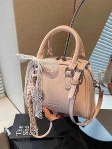 Pink matte leather bowling bag with twin handles and delicate white lace bow detail