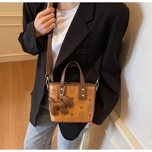Détail d'un sac seau marron vintage avec motif monogramme et pendentif chien mignon