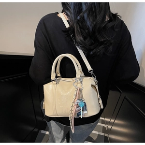 Detail of beige faux leather Boston bag with embossed lettering and stylish charms