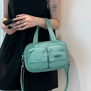 Detail of mint green nylon utility bag with front flap pockets and adjustable strap