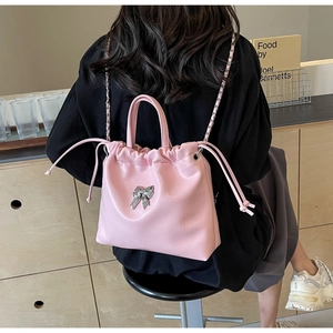 Detailed view of pink pleated drawstring bag with silver bow accent and chain strap
