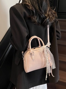 Pink Boston style handbag with adjustable strap and lace bow charm on a model