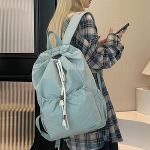 Detail view of mint green nylon drawstring backpack with stylish white tassel cords