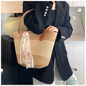 Detail of straw tote bag with brown leather handles and rose embroidery lace scarf