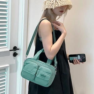 Detail of mint green nylon utility crossbody bag with functional double front pockets