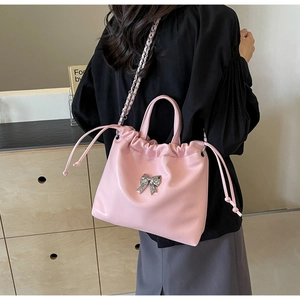 Detail of pink bow shoulder bag with silver rhinestone knot and woven chain strap