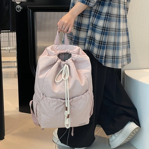 Detail of pink nylon drawstring backpack featuring functional front pockets and cotton ropes