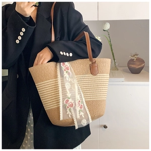 Close-up of straw tote bag featuring white lace ribbon and pink rose embroidery details