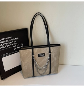 Détail du sac cabas en toile beige avec chaînes argentées et finitions en cuir noir