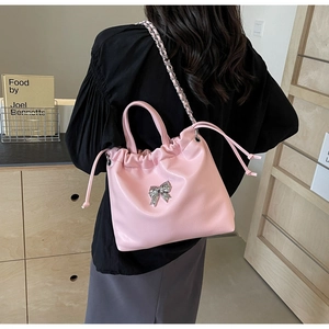 Detail of pink bow handbag with drawstring closure and silver chain strap for women