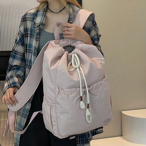 Detail of pink nylon drawstring backpack with side pockets and soft cotton rope straps