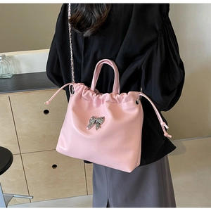 Detail of pink bow handbag with pleated drawstring closure and silver chain strap