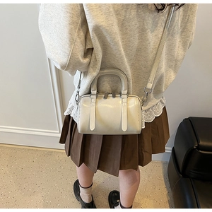 Detail of cream white Boston bag showing double handles and leather texture on model