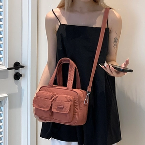 Brick red nylon utility handbag featuring multiple pockets and adjustable shoulder strap