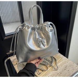 Close-up of silver bow drawstring handbag with metallic chain strap and textured leather